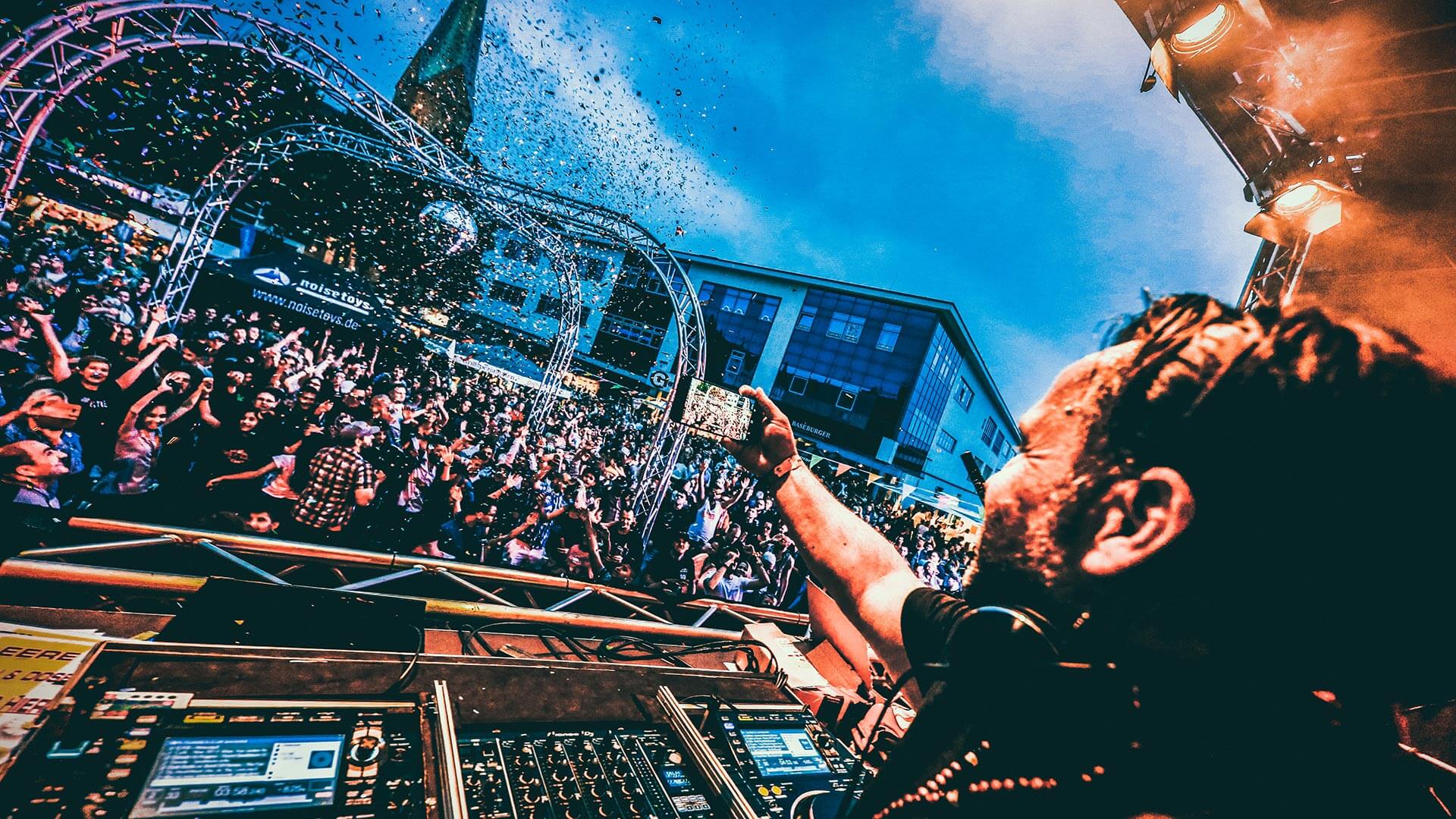 Blick vom DJ-Pult über eine feiernde Festivalmenge mit Konfetti