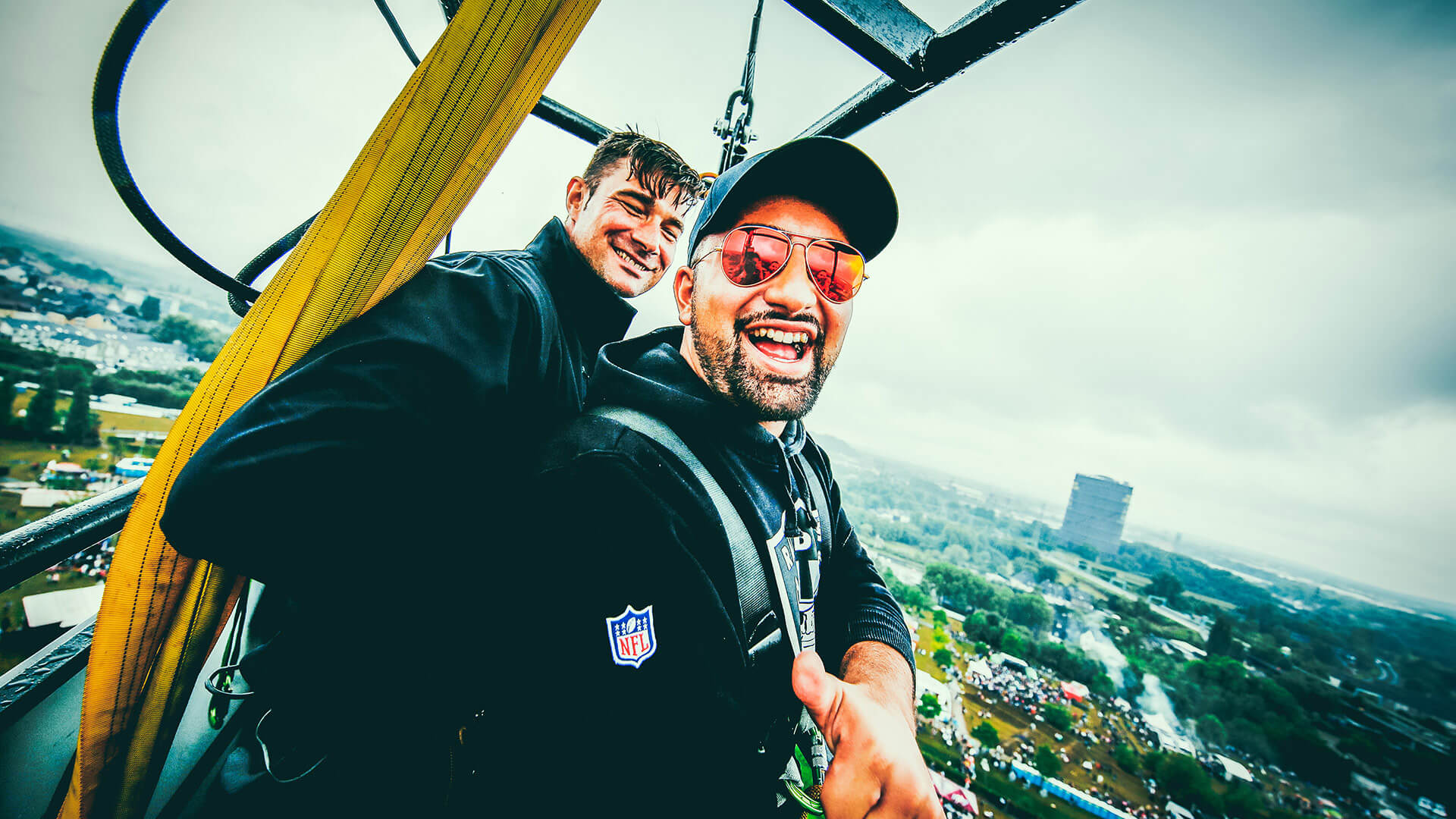 Zwei Männer machen hoch über der Stadt ein Selfie in einer Bungee-Gondel